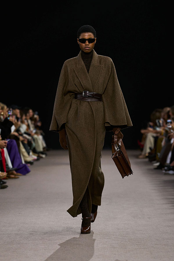 Max-Mara-Show Herbst/Winter 2025 – Look mit schwarzer Sonnenbrille im Maskendesign und langem Gürtel aus bronzebraunem Leder.