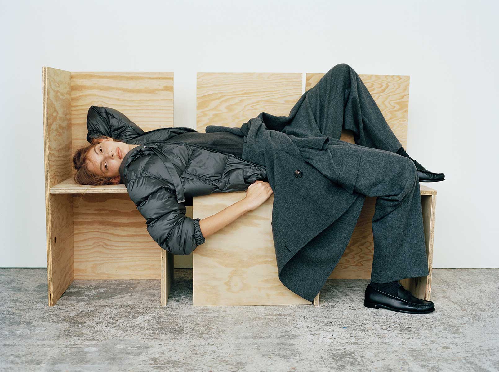 Das liegende Model trägt eine Max Mara The Cube Daunenjacke aus wasserabweisendem Funktionsgewebe & eine Oversize-Hose.