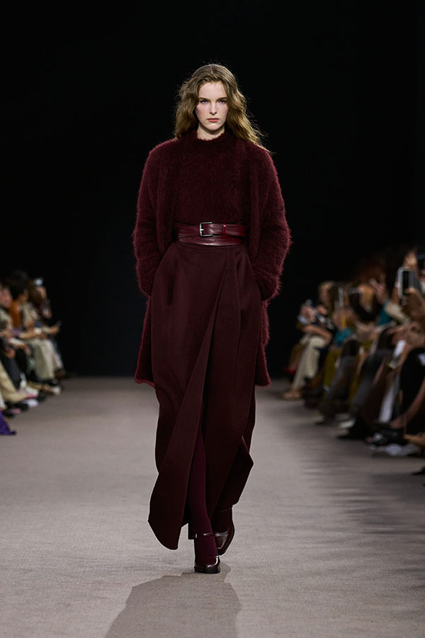 Max-Mara-Show Herbst/Winter 2025 – Look in Kirschrot mit Pullover, Gürtel, Cardigan, langem Rock und Mary-Jane-Schuhen.