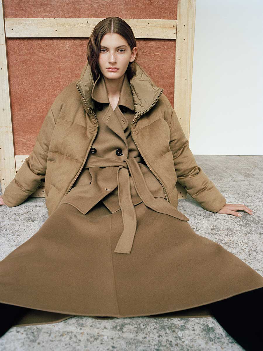 Das Model trägt einen Mantel unter der wendbaren Max Mara The Cube Daunenjacke aus Kamelhaardrap und wasserabweisendem Taft.